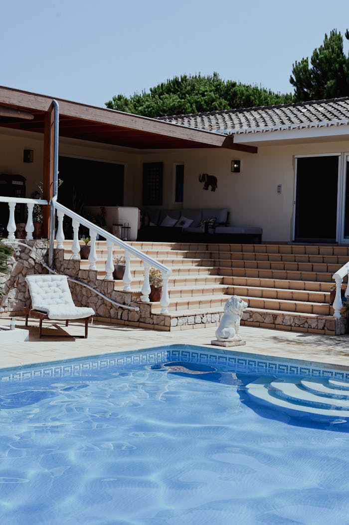 Elegant villa featuring a sparkling pool, sunny patio, and comfortable lounge chairs.